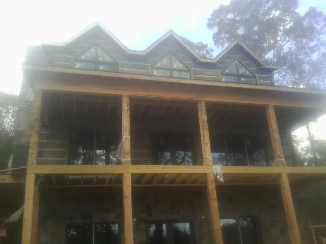 Dormers and porch framing on a large log home under construction — Roof Coating work by our crew in Millen