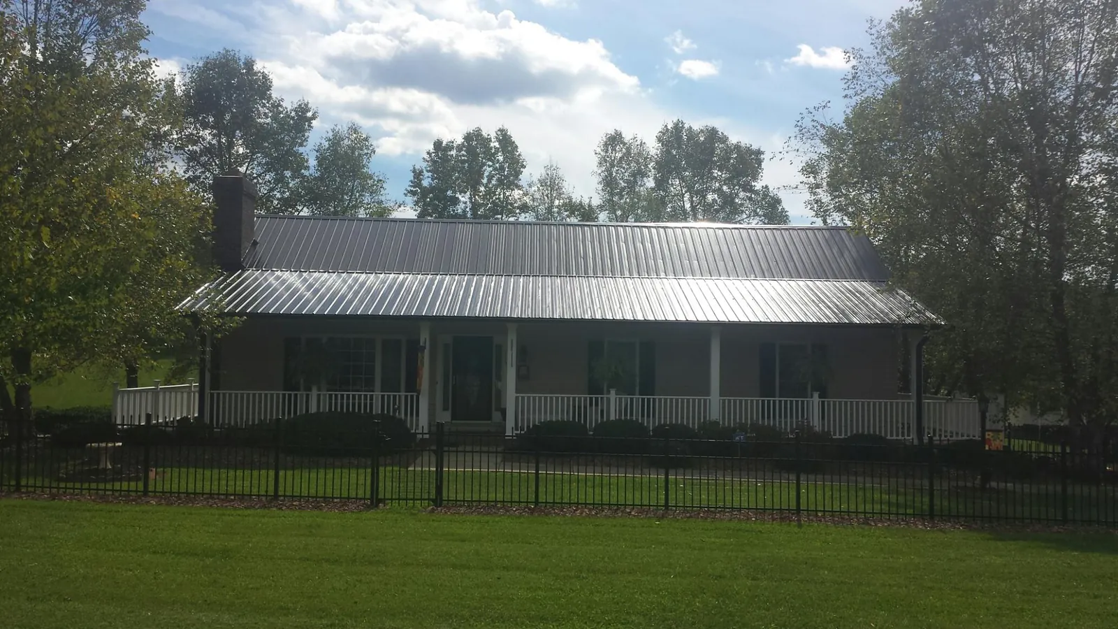 Gray metal roof on a brick ranch with a full width front porch — Gutter Guard Installation work by our crew in Millen